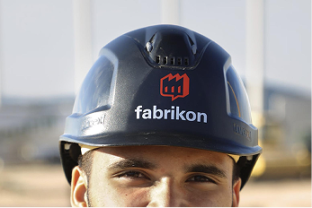 Arbeiter mit einem Sicherheitsschutzhelm, auf dem das Logo von "fabrikon" sichtbar ist.